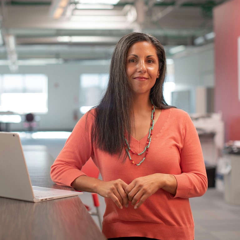 Woman standing next to an open laptop
